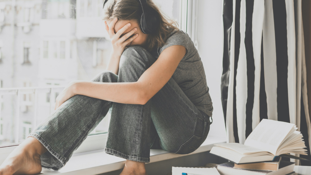 Jeune fille désespérée avec ses devoir et leçons. L'adolescente porte un casque audio