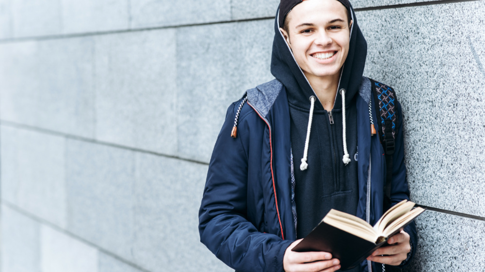 adolescent souriant avec un livre en main